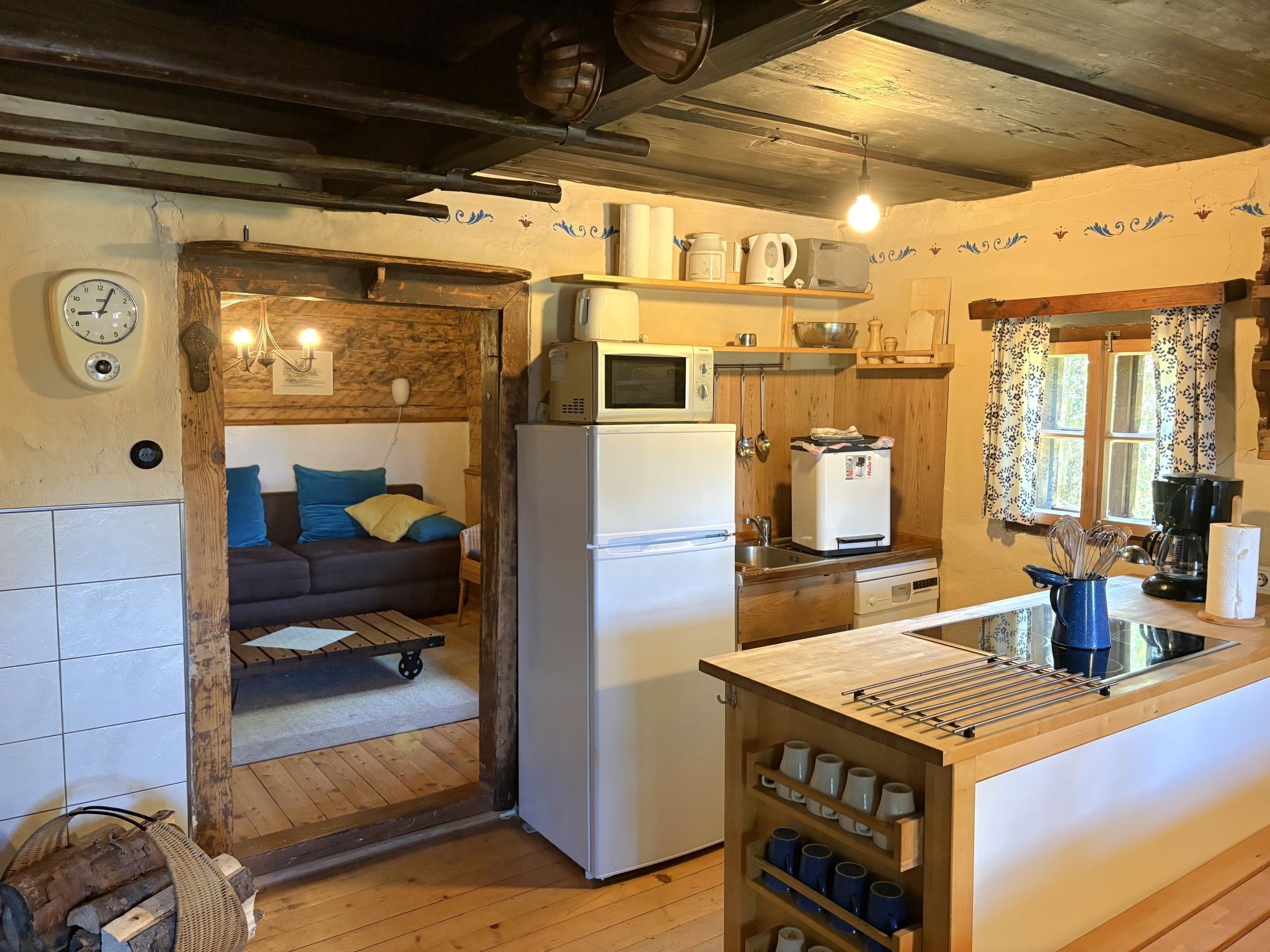 A rustic kitchen with a refrigerator, microwave, and wooden shelves.