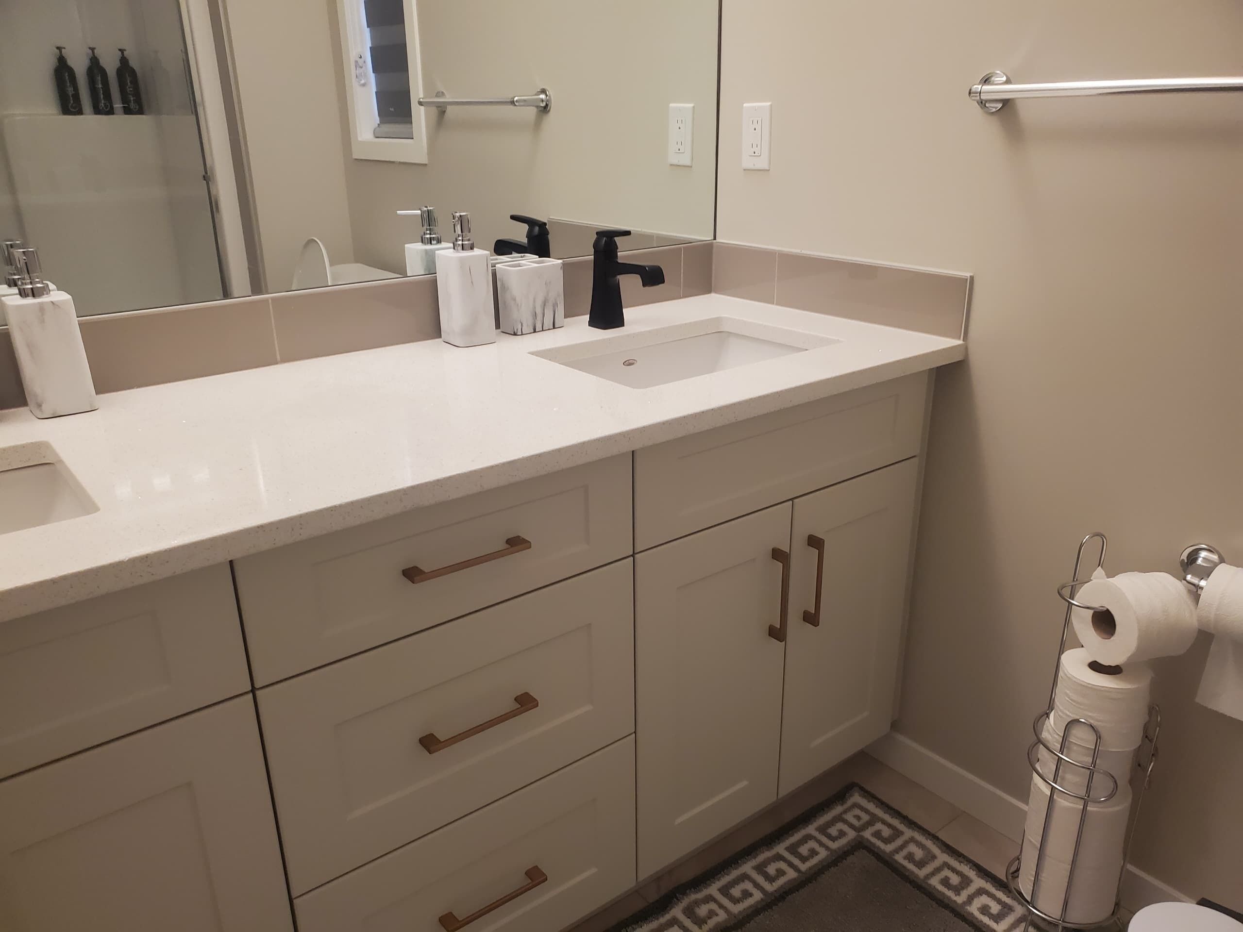 A bathroom with a white sink, vanity, and storage cabinets.
