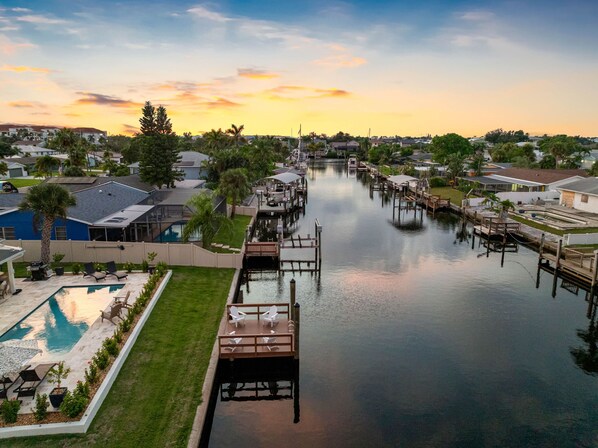 A residential area with a dock extending into a calm water body, surrounded by houses and greenery.