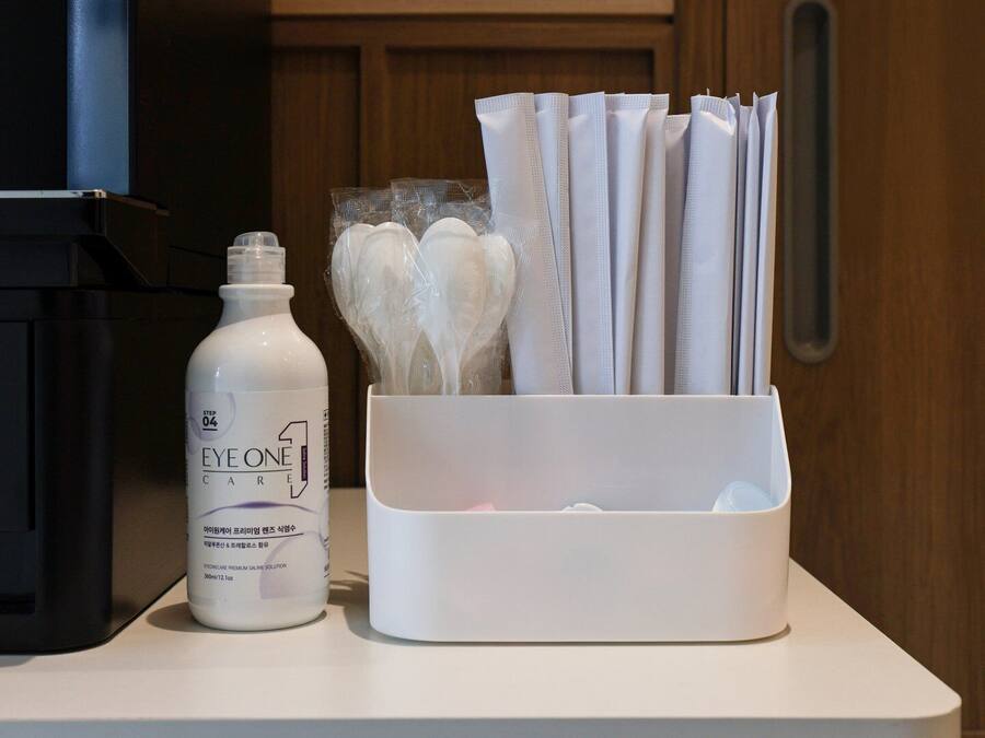 Un plan de travail sur lequel se trouve une bouteille blanche étiquetée « EYE ONE CARE » et un organiseur blanc contenant divers objets.