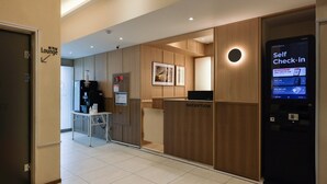 A reception area with a self-check-in kiosk, a reception desk, and a lounge sign.