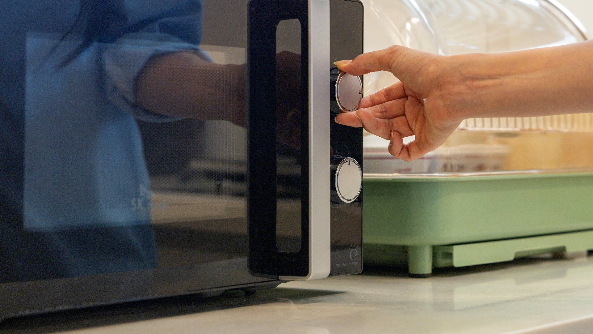 Una mano ajustando el dial de un microondas.