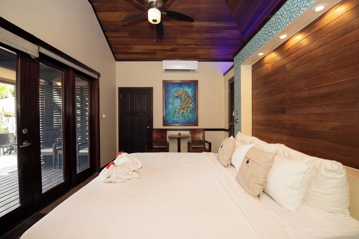 Une chambre d’hôtel avec un grand lit, un plafond en bois et un tableau au mur.