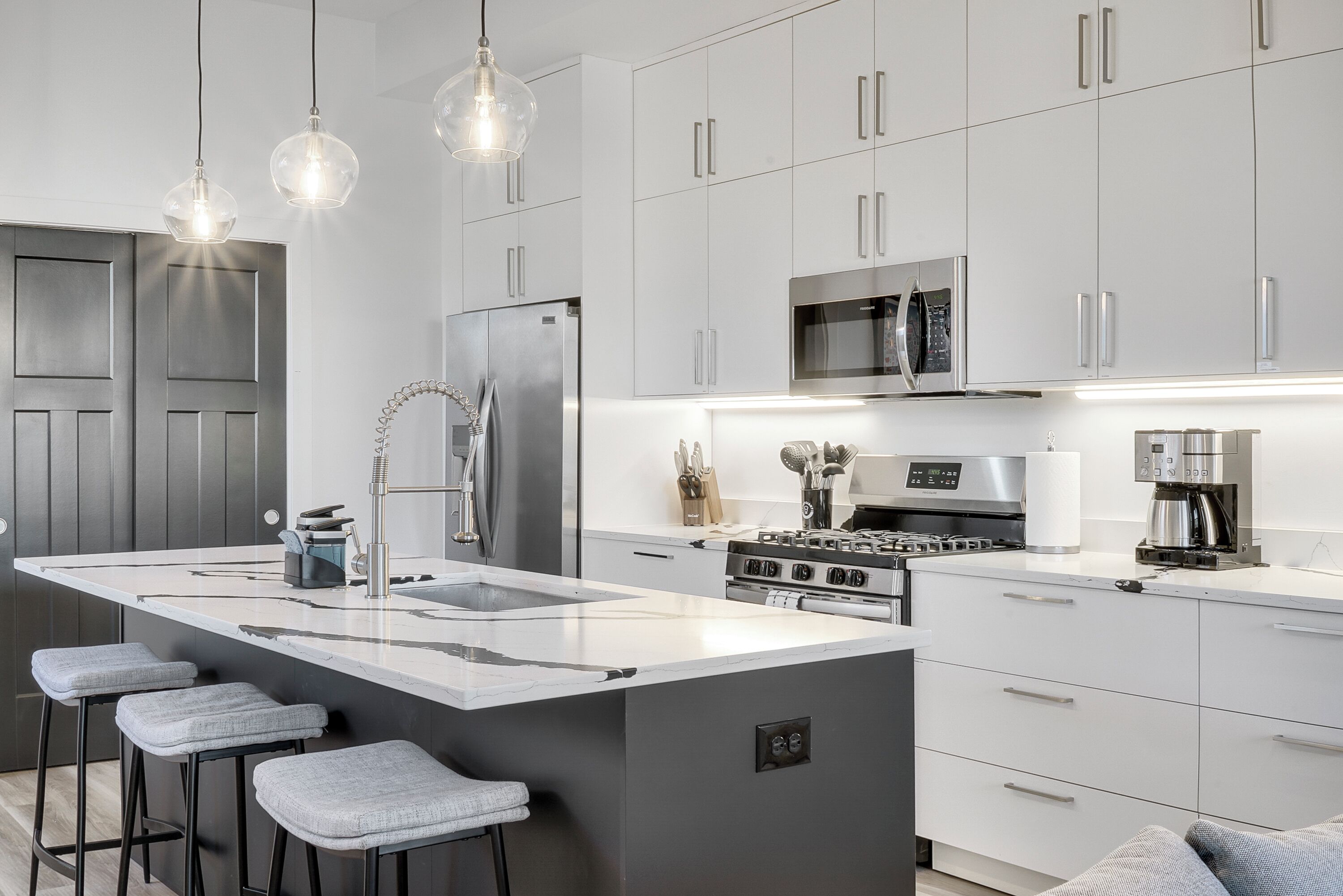 A modern kitchen with a central island, stainless steel appliances, and bar stools.