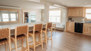 Una cocina moderna con taburetes de madera, una isla integrada y un lavavajillas.