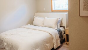 Un dormitorio con cama, ventana con persianas, aire acondicionado y un cuadro en la pared.
