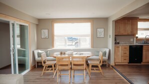 Una cocina moderna con armarios de madera, una mesa de comedor con sillas y un ventanal grande.