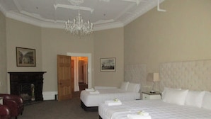 A hotel room with two beds, a chandelier, a fireplace, and framed pictures on the walls. - Valmai House & Motel (Cambridge)