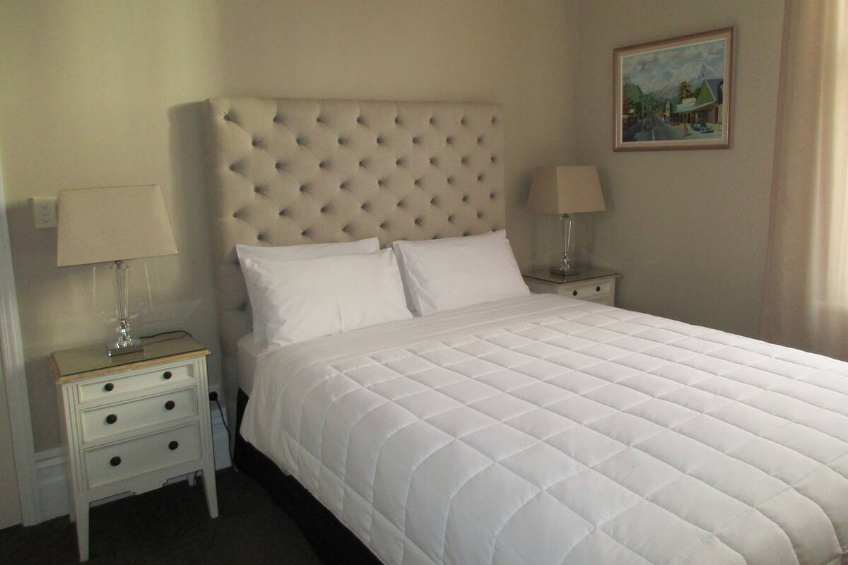 A neatly made bed with a tufted headboard in a hotel room.