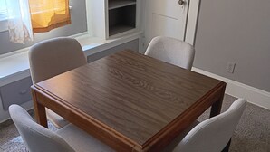 Un comedor con mesa de madera y cuatro sillas.