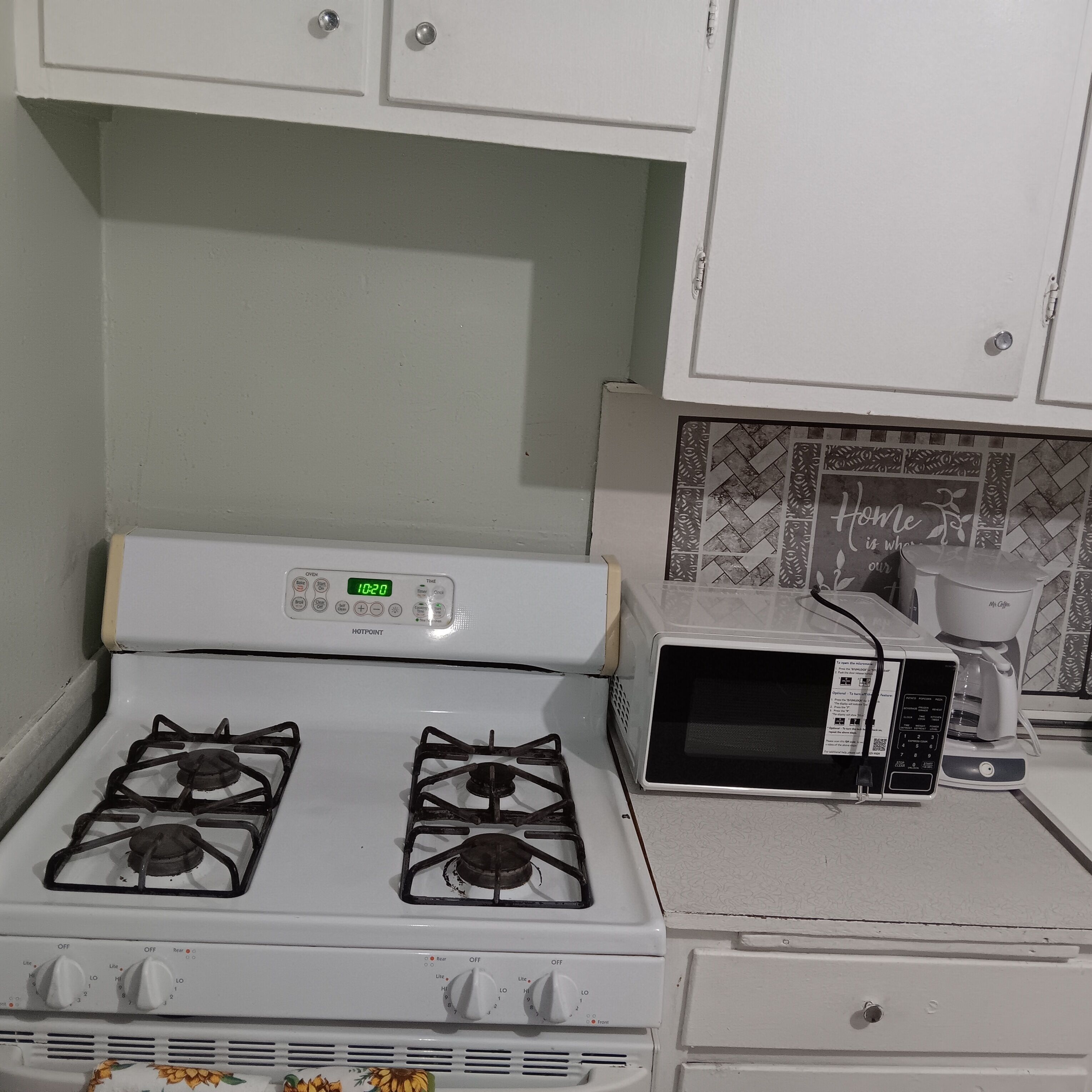 A kitchen with a white stove, a microwave, and a coffee maker.