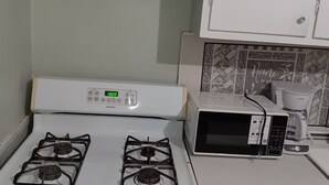 Una cocina con estufa blanca, microondas y cafetera.