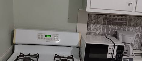 A kitchen with a white stove, a microwave, and a coffee maker.