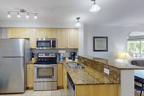 A modern kitchen with stainless steel appliances, granite countertops, and wooden cabinets.