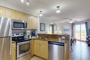 A modern kitchen with stainless steel appliances, wooden cabinets, granite countertops, and a dishwasher.