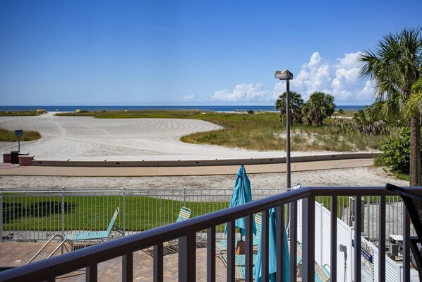 A beach view with a clear sky, a sandy beach, and a road curving away from the viewer.