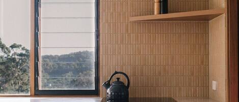 A modern kitchen with wooden cabinetry, a built-in oven, and a window overlooking a scenic view.
