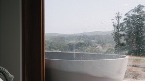 A large, white, speckled bowl on a wooden surface, viewed through a window with a view of a hilly landscape. - Wildwood Barn: New Luxe Home, Valley Views, Outside Bath, Firepit & Ocean Views (Yallingup)