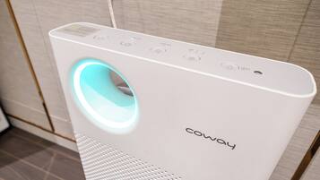 A white Coway portable air purifier with a blue light, control buttons, and a brand name on the front.