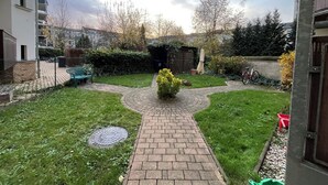 Ein wohnlicher Garten mit einem gepflasterten Weg, einer grünen Bank und einer kleinen Gartenanlage.
