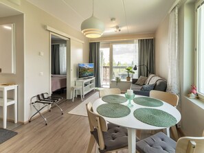 A modern living room with a dining area, a television, and a view of the outdoors. - Aurinkorinne 1 as 24 by Interhome (Kittilä)