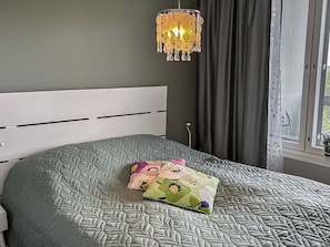 A bedroom with a bed, a chandelier, and a window with curtains. - Aurinkorinne 1 as 24 by Interhome (Kittilä)