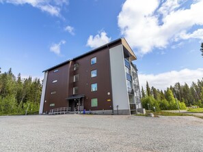A multi-story building with a modern design, featuring a flat roof and a mix of glass and solid panel windows. - Aurinkorinne 1 as 24 by Interhome (Kittilä)