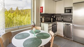 Una cocina moderna con un amplio ventanal, electrodomésticos de acero inoxidable y un comedor con una mesa redonda y sillas.