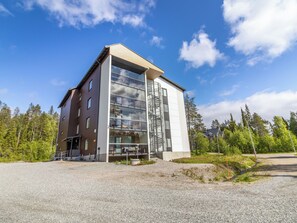 A modern building with a large glass facade, a metal spiral staircase, and a gravel driveway. - Aurinkorinne 1 as 24 by Interhome (Kittilä)