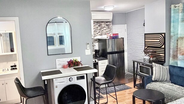 A compact living space with a kitchenette, a washing machine, a dining area, and a bedroom. - Rental studio unit in Queen Village of Philadelphia (Philadelphia)