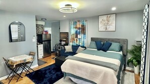 A modern bedroom with a large bed, a desk, and a dining area. - Rental studio unit in Queen Village of Philadelphia (Philadelphia)