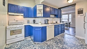 Una cocina con armarios azules, una estufa blanca y baldosas de suelo estampadas.