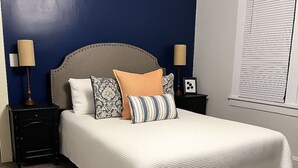 Un dormitorio con una cama grande, dos mesitas de noche y una ventana con persianas.