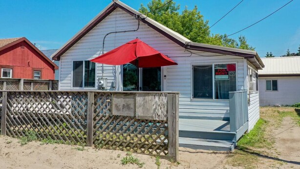 A single-story house with a red umbrella, a 'For Rent' sign, and a wooden fence. - Remi-Loo's Bay Escape: Cottage in Sunset Bay (Sunset Bay)