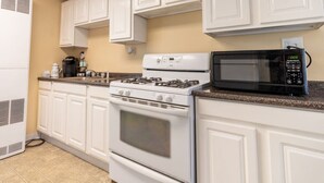 A kitchen with white cabinets, a stove, a microwave, and a coffee maker. - Remi-Loo's Bay Escape: Cottage in Sunset Bay (Sunset Bay)