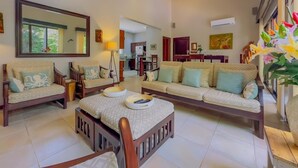 A spacious living room with a large sofa set, a coffee table, and a dining area in the background. - Sombras #704 Beachside Escape Spacious 3BR Condo with Terrace (Playas del Coco)