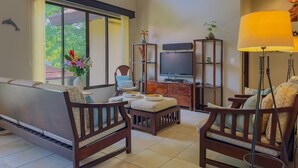 A living room with a sofa, two armchairs, a coffee table, a TV, and a lamp. - Sombras #704 Beachside Escape Spacious 3BR Condo with Terrace (Playas del Coco)