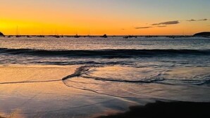 A beach with calm waves and a sunset in the background. - Sombras #704 Beachside Escape Spacious 3BR Condo with Terrace (Playas del Coco)
