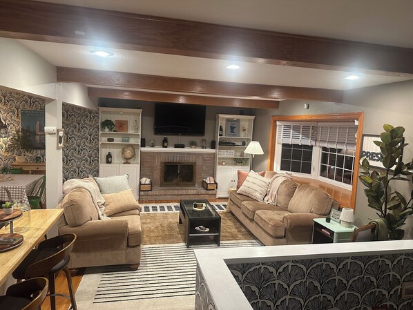 Télévision, cheminée, lecteur de DVD, livres