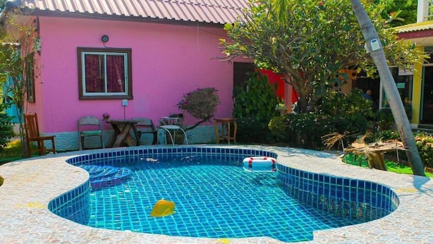 A swimming pool with a tiled edge, a lifebuoy, and a pink building in the background. - Wave point resort  (Pattaya)