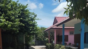 A quiet street with a house on the right, featuring a pink roof and blue walls. - Wave point resort  (Pattaya)