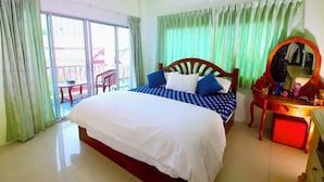 A hotel room with a large bed, a desk with a mirror, and a view of the outside through a sliding door. - Wave point resort  (Pattaya)
