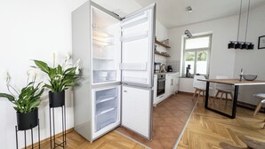 A modern kitchen with a built-in refrigerator, wooden flooring, and a dining area with a table and chairs. - FirstClass 2-room apartment (Leipzig)