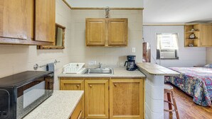 A compact kitchen with wooden cabinets, a microwave, a coffee maker, and a sink. - On-Site Hiking Trails: Cozy Lake Whitney Studio! (Whitney)