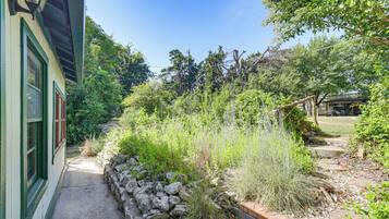 A garden pathway leading to a building with a stone wall and various plants.