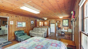 A cozy cabin with a bed, a green leather chair, a sofa, a dining area, and a kitchen. - On-Site Trails! Cozy Whitney Cottage 2 Mi to Lake (Whitney)