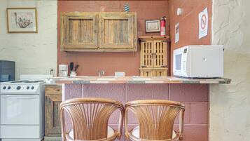 Une cuisine équipée d’une cuisinière, d’un four à micro-ondes et de deux chaises en osier.