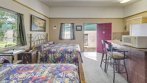 A bedroom with two beds, a desk, a chair, a microwave, and a red door leading to a bathroom. - Patio & Trail Access: Lake Whitney Studio! (Whitney)