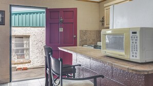 A kitchen with a red door, a white microwave, and a chair. - Patio & Trail Access: Lake Whitney Studio! (Whitney)