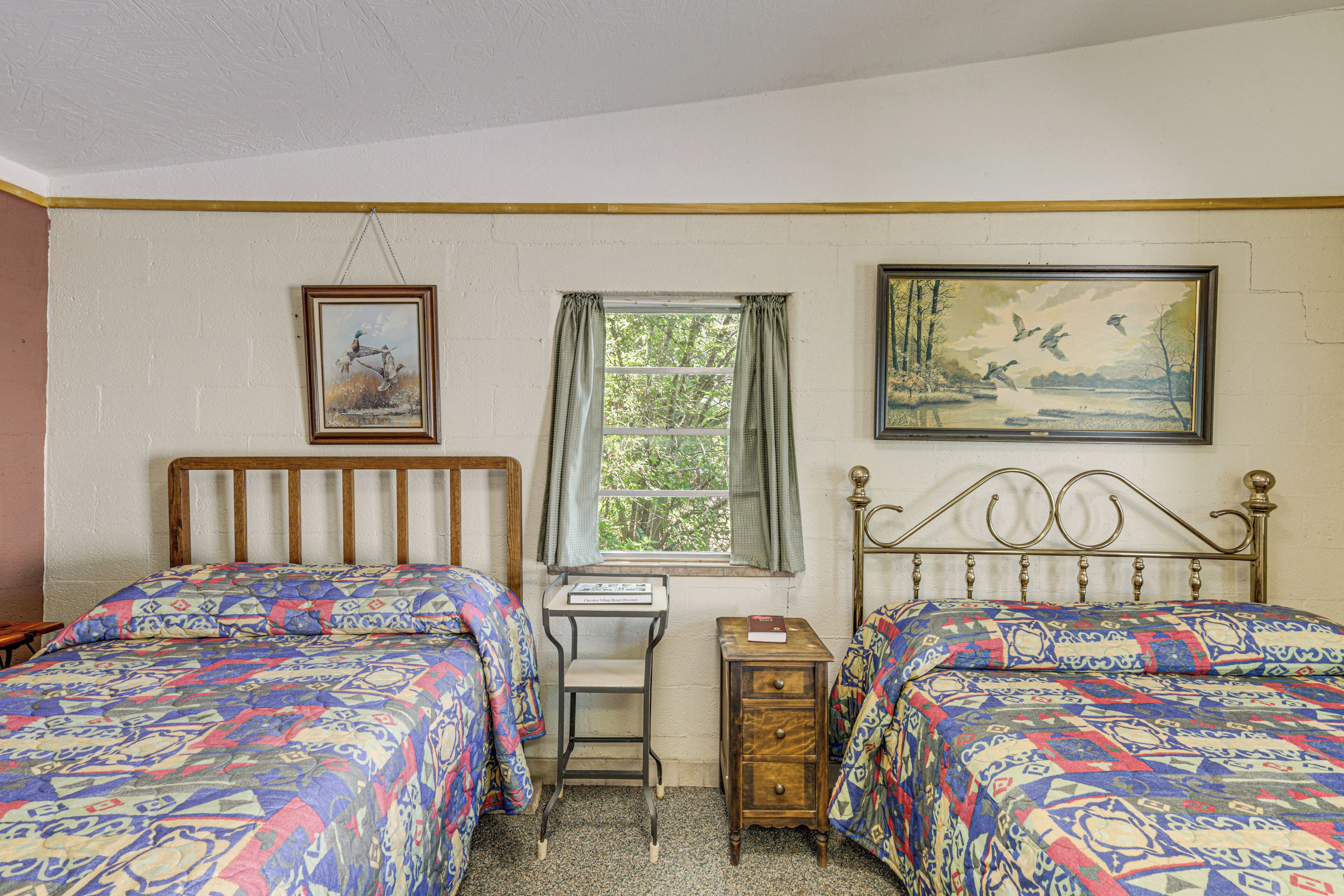 A bedroom with two beds, a desk, and a window.